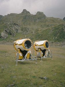 Gelbe Schneekanonen auf einer Bergwiese im Skigebiet Stubaier Gletscher